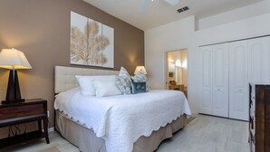 A bedroom with a bed, bedside lamps, a nightstand, a wall art piece, a wardrobe, and a ceiling fan. - North Hampton Pool House (Davenport)