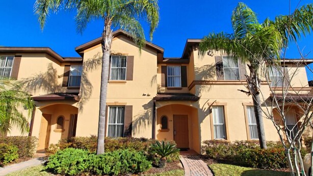A multi-story residential building with a beige exterior, multiple windows, and a brick pathway leading to the entrance. - 716TL (Davenport)