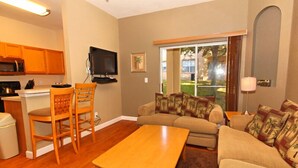 A compact living space with a kitchenette, a sofa set, a dining table, and a television. - 716TL (Davenport)