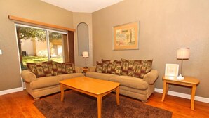 A living room with a sectional sofa, a wooden coffee table, a small side table, and a lamp. - 716TL (Davenport)