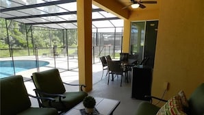 A covered outdoor seating area with a pool, chairs, a table, and a ceiling fan. - Crane's Roost Villa (Davenport)