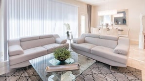 Ein modernes Wohnzimmer mit zwei Sofas, einem Glastisch und einer Topfpflanze.