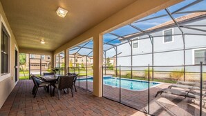 A covered patio with a pool, outdoor furniture, and a view of neighboring houses. - Rolling Fairway Home (Davenport)