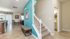 A spacious living area with a kitchen, a dining area, and a staircase leading to an upper level. - Rolling Fairway Home (Davenport)