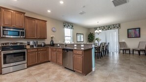 A spacious kitchen with wooden cabinets, stainless steel appliances, and a central island. - Rolling Fairway Home (Davenport)