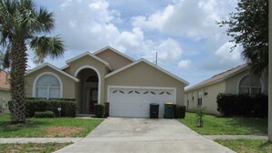 A single-story house with a garage, a front lawn, and a palm tree. - Captain Jack's Getaway (Kissimmee)