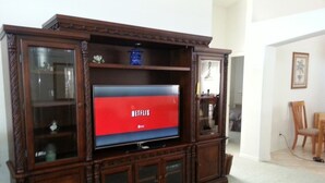 A wooden entertainment center with a flat-screen TV displaying the Netflix logo. - Captain Jack's Getaway (Kissimmee)