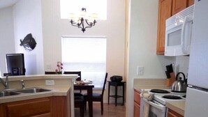 Une cuisine compacte équipée d’une cuisinière, d’un four à micro-ondes et d’un évier. Un coin repas avec une table et des chaises est également disponible.
