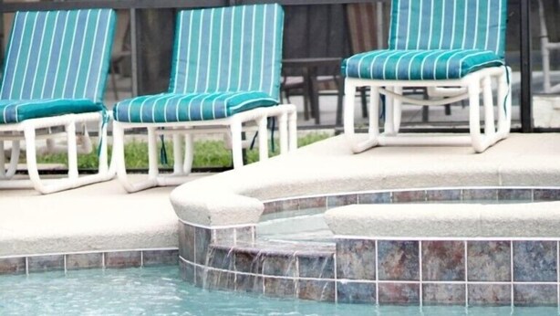 Un espace piscine comprenant trois chaises longues et un petit jacuzzi.