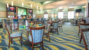 A spacious restaurant with a bar area, multiple tables and chairs, and a patterned carpet. - 1408 Wexford Way (Davenport)