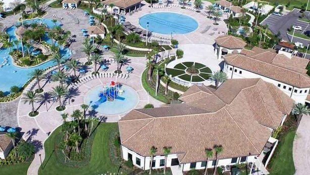 An aerial view of a resort with multiple swimming pools, a central water feature, and a large building with a tiled roof. - 1408 Wexford Way (Davenport)