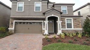 A two-story house with a garage, stone accents, and a brick driveway. - 1408 Wexford Way (Davenport)