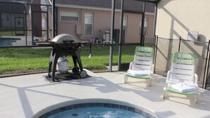 Zona de piscina amb gandules i una barbacoa.