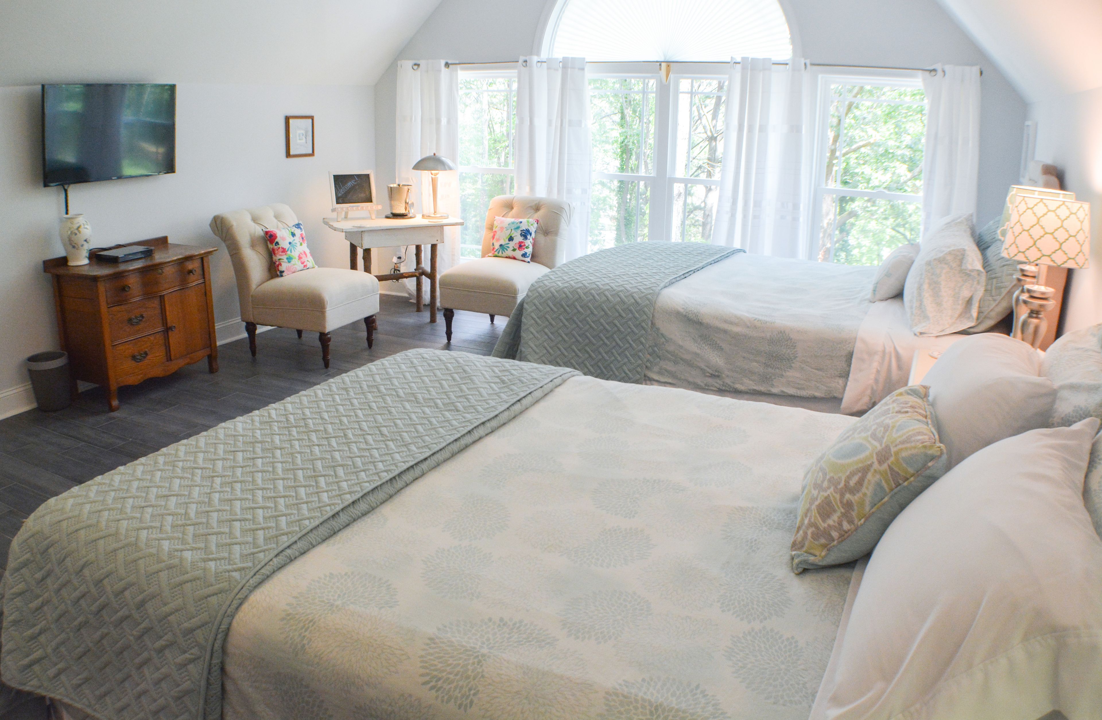Une chambre avec deux lits, un bureau, une chaise et un téléviseur.