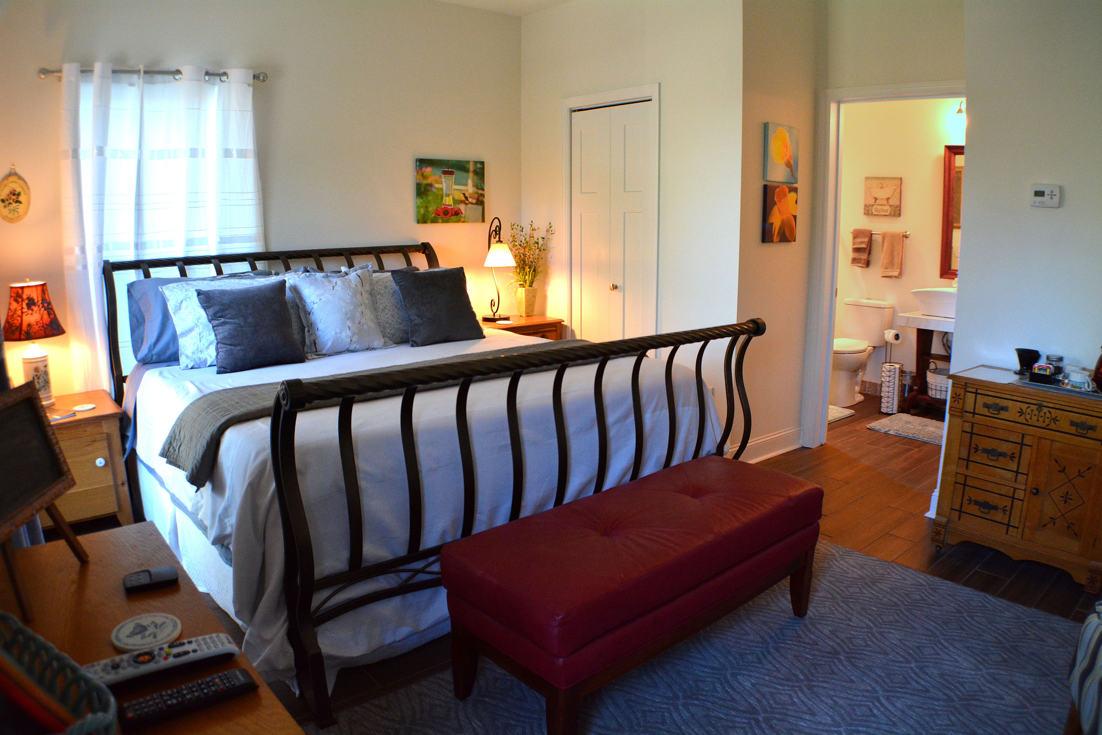 Une chambre à coucher avec un lit, une table de chevet, une lampe et un banc rouge.