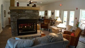 A cozy living room with a stone fireplace, comfortable seating, and a dining area. - St Francis Cottage (Chattanooga)