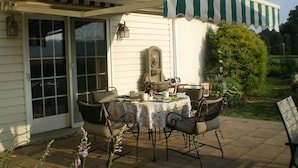An outdoor patio with a table and chairs, a stone fountain, and a garden view. - Red Cardinal Bed and Breakfast (Carlisle)