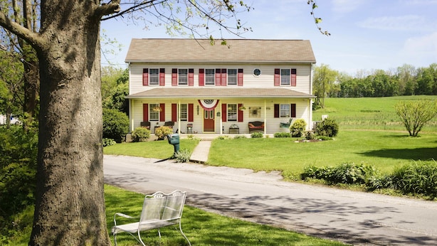 A two-story house with a front porch, a mailbox, and a bench in the foreground. - Red Cardinal Bed and Breakfast (Carlisle)