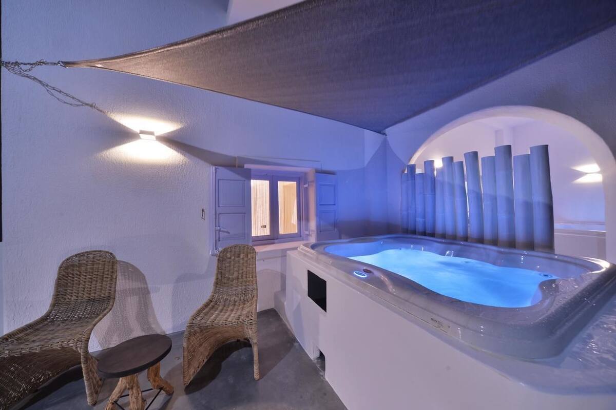 A spa area with a hot tub, wicker chairs, and a covered seating area.