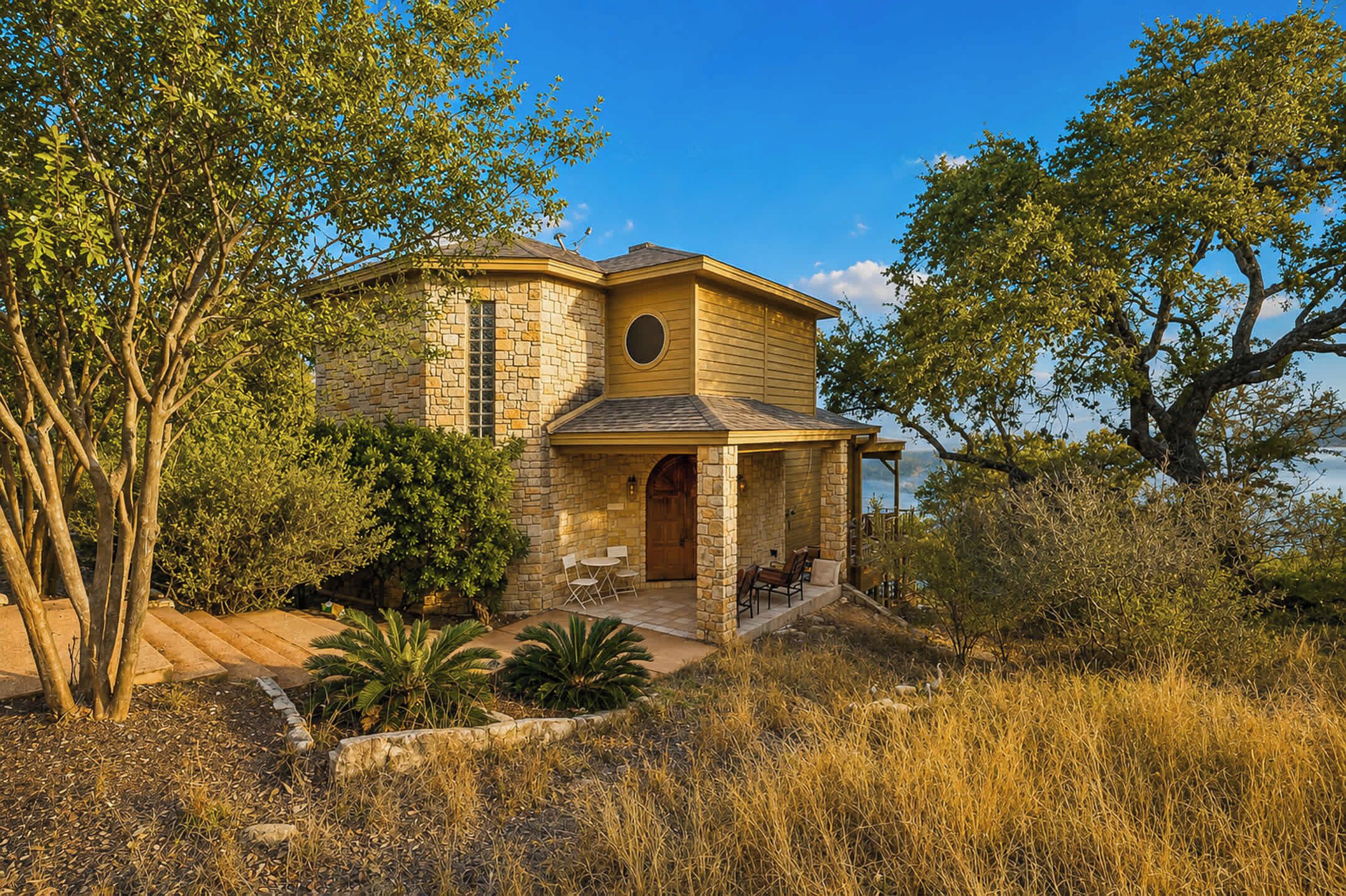 A stone house with a porch, outdoor seating, and a view of the surrounding landscape.