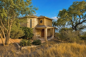 A stone house with a porch, outdoor seating, and a view of the surrounding landscape.