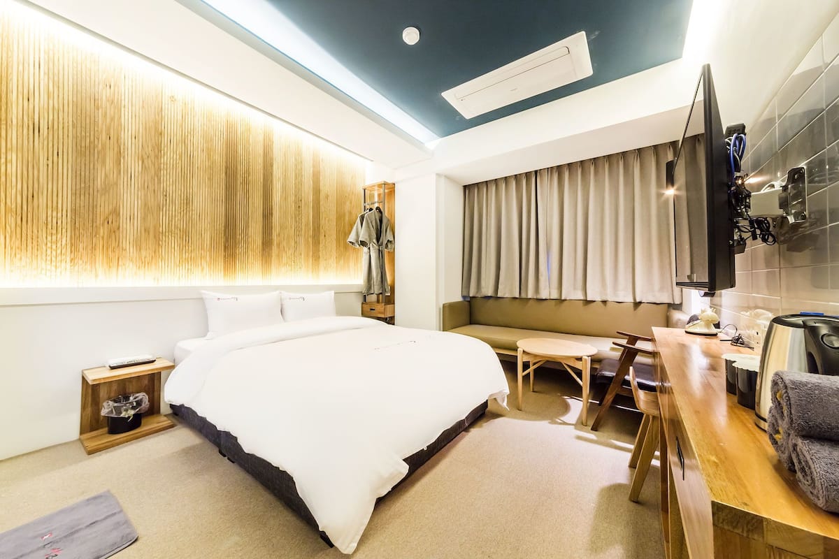 Een moderne hotelkamer met een groot bed, een bureau met stoel, een televisie en een kledingkast.