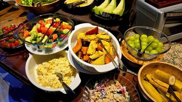A buffet with various dishes including salads, fruits, and pasta salad.