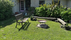 A house with a green roof, a front door, and a bench in the yard.