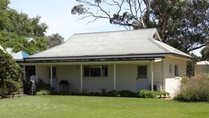 A single-story house with a flat roof, a front porch, and a well-maintained lawn.