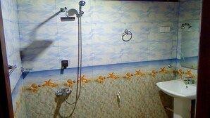 A bathroom with a shower, a sink, and a tiled wall with a sea-themed design. - Villa Peacock (Hikkaduwa)