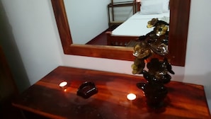 A wooden vanity with a mirror, a small vase with a plant, and two candles. - Villa Peacock (Hikkaduwa)