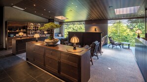 A modern kitchen with a large island, built-in shelves, and a seating area with a view of the outdoors. - Hakone Suishoen (Hakone)