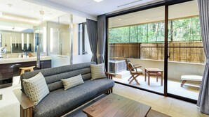 A modern living room with a sofa, coffee table, and a sliding glass door leading to a balcony with outdoor furniture. - Hakone Suishoen (Hakone)