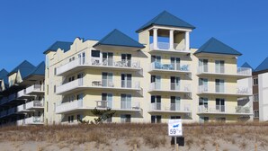 A multi-story hotel with balconies, a beach view, and a sign indicating the address. - ADAGIO#207 BEAUTIFUL 3 BED/3 BATH OCEAN BLOCK CONDO W/INDOOR POOL STEPS TO BEACH (Ocean City)