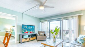 A living room with a television, a sofa, a coffee table, and a ceiling fan.
