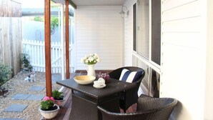 Un patio cubierto con una mesa y sillas, un florero con flores y plantas en macetas.