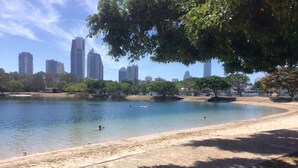 Un parque con un lago, árboles y un horizonte urbano al fondo.