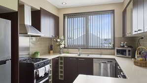 Een moderne keuken met roestvrijstalen apparatuur, een groot raam en uitzicht op buiten.