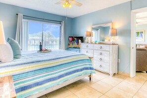 A bedroom with a bed, a dresser, a TV, and a window with curtains.