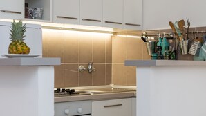 A modern kitchen with white cabinets, a built-in oven, and a countertop with a pineapple.