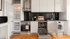 A modern kitchen with white cabinetry, a built-in oven, a dishwasher, and a washing machine. - Chiado | STYLISH & GREAT VIEW | Family-Friendly (Lisboa)