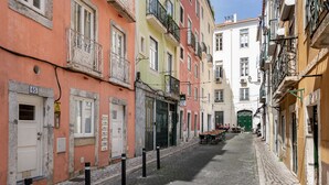A narrow cobblestone street lined with colorful buildings, some with balconies and outdoor seating areas. - Chiado | STYLISH & GREAT VIEW | Family-Friendly (Lisboa)