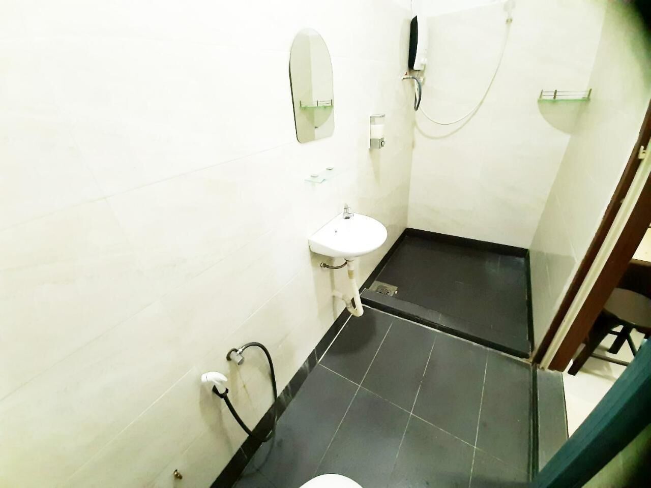Un baño pequeño con un lavamanos blanco, un espejo y una ducha.