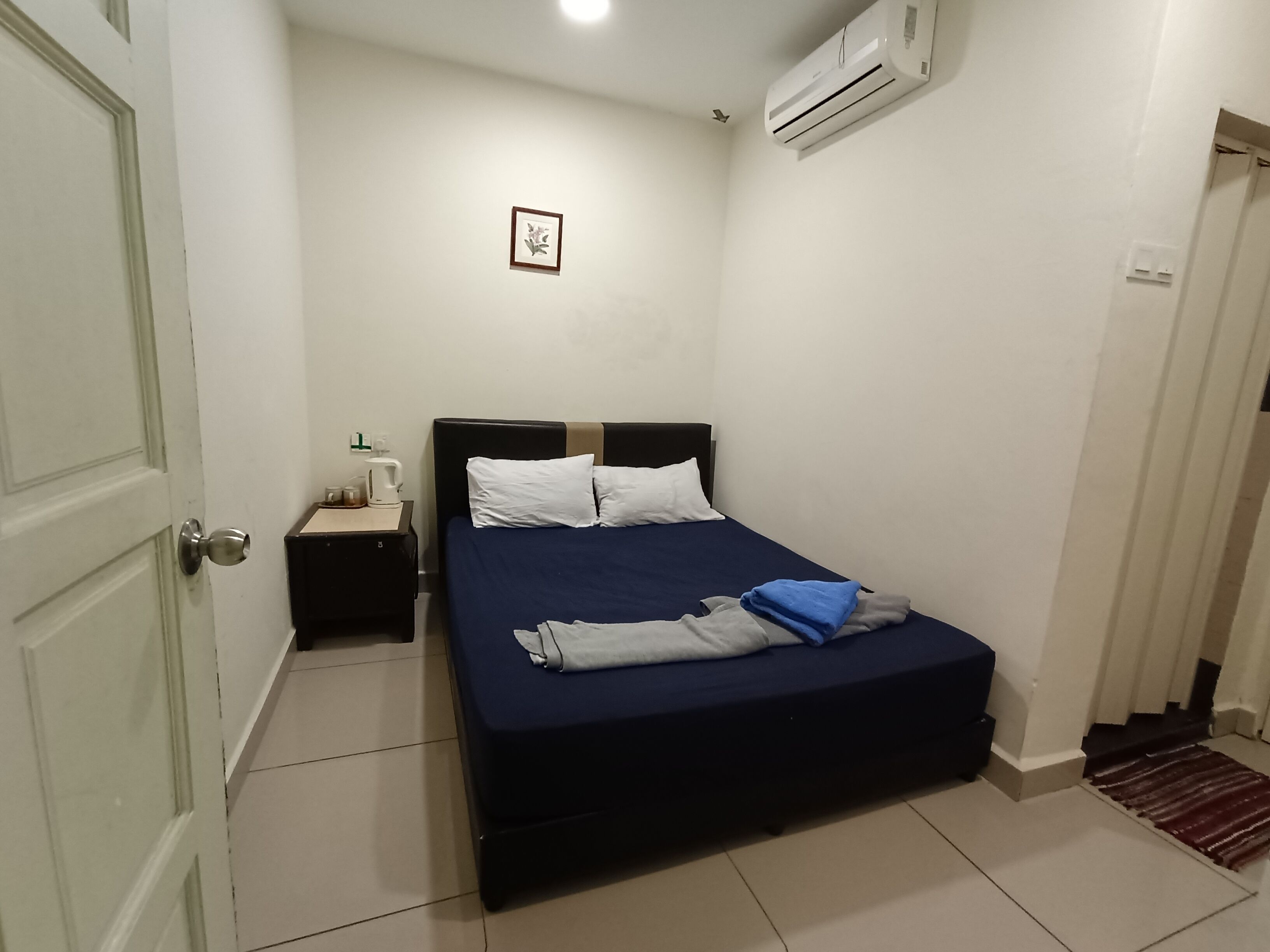 Una camera da letto con un letto, un comodino, un condizionatore e una porta.
