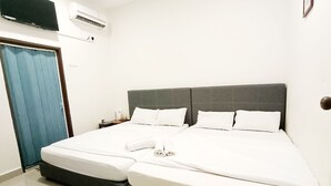 A neatly made bed with white linens and pillows, a grey headboard, and a blue curtain on the left. - MN Ferringhi Inn (George Town)