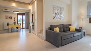 Ein modernes Wohnzimmer mit einem grauen Sofa, einem gelben Tisch und einem Bild an der Wand.