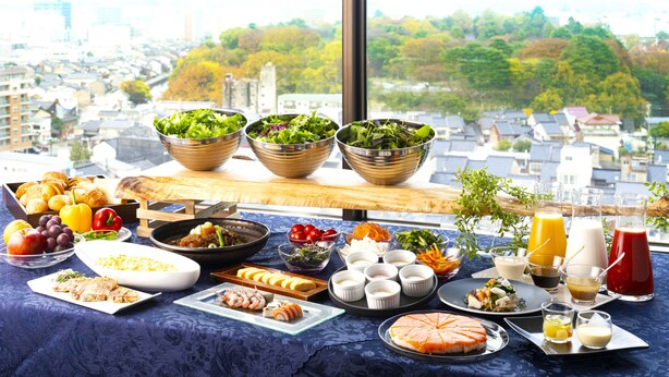 Un buffet de petit-déjeuner proposant une variété de plats et de boissons, le tout dans un cadre offrant une vue sur la ville.