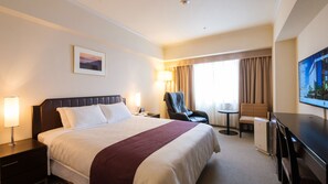 Una habitación de hotel con una cama grande, un escritorio, una silla, un televisor y una ventana con cortinas.