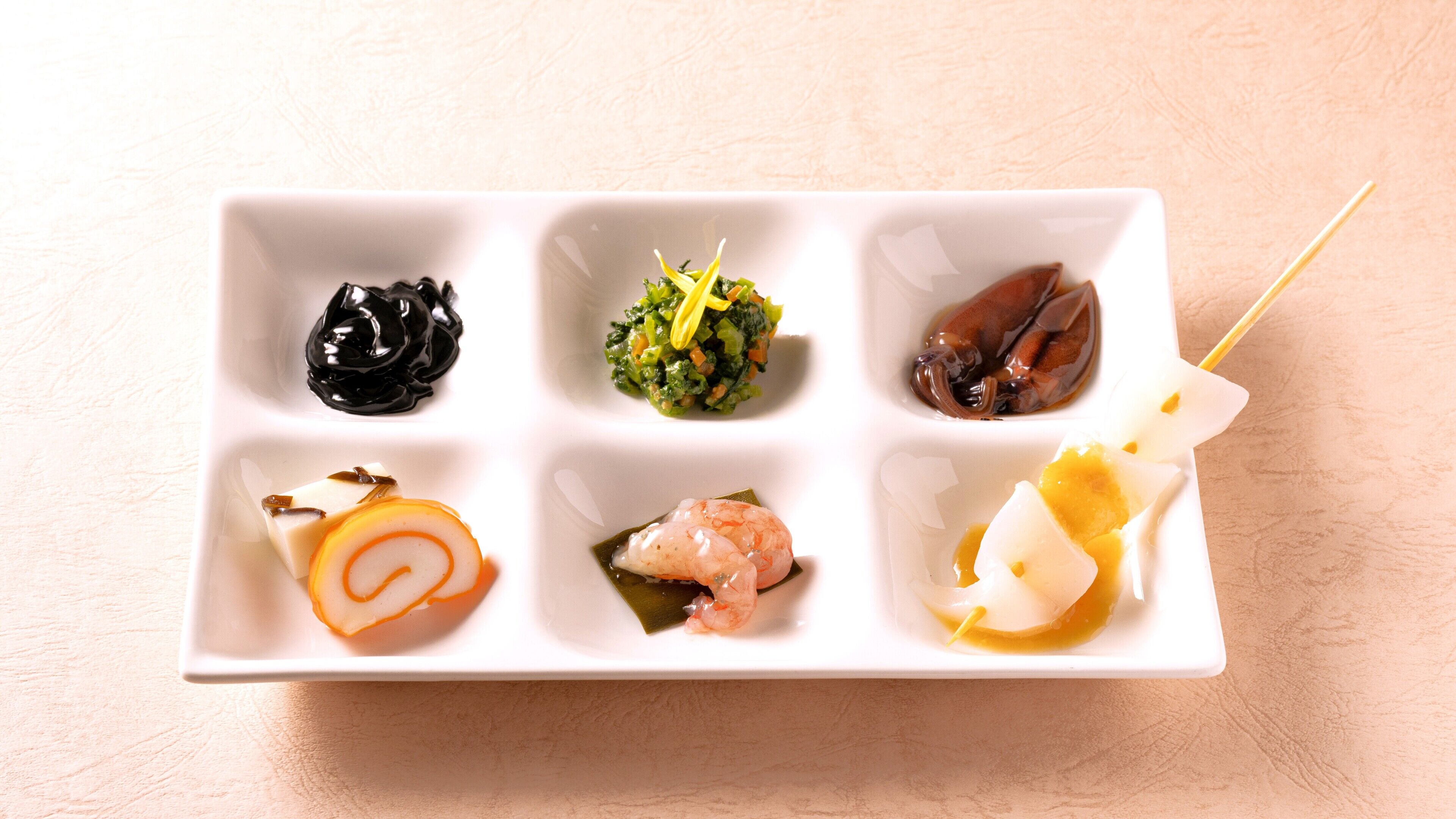 A white rectangular plate with six different food items arranged in two rows.