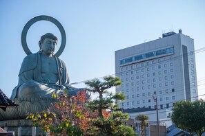 A large Buddha statue in a public square with a modern building in the background. - Hotel New Otani Takaoka (Takaoka)